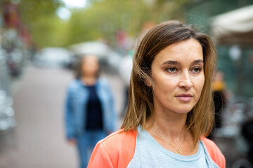 Closeup portrait of adult brown-haired woman walking along city street in warm autumn day