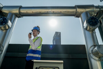 Engineer in safety gear conducts inspection on large industrial water tanks on a building rooftop....
