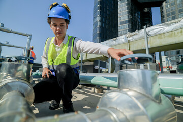 engineer inspecting HVAC equipment with a tablet on a building rooftop. An engineer attentively...