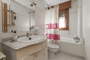 A bathroom with a white wooden cabinet with a marble countertop and a white porcelain sink under a frameless mirror