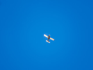 Small ultralight airplane with overhead wing and single propeller flying in sunset sky.