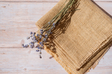 Dried lavender flowers on burlap textile material on wooden background. Copy space for your text....