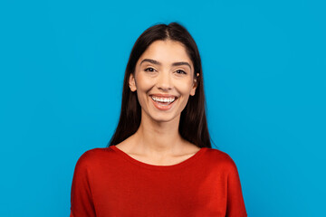 A woman wearing a red top smiles directly at the camera, radiating a sense of joy and confidence in...