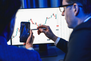 Two stock exchange traders researching data on smartphone and laptop screen server of dynamic...