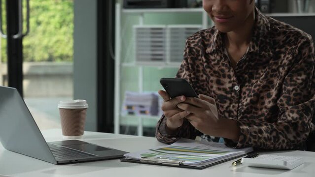 A young African American woman in a blue formal shirt with afro brown hair works as a product designer in a modern office, utilizing skills in design, CAD, CNC, and CNF.