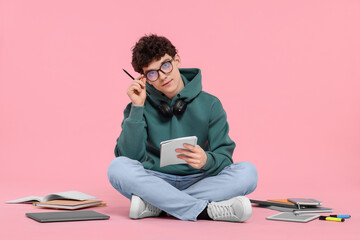 Portrait of student with notebook and stationery sitting on pink background