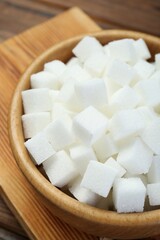 White sugar cubes in wooden bowl, closeup
