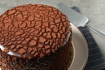 Delicious chocolate truffle cake and server on table, closeup