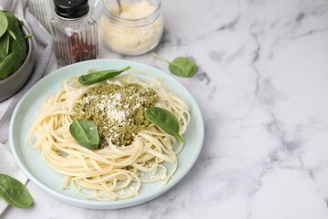 Tasty pasta with spinach, cheese and sauce on white marble table, space for text