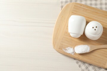 Spice shakers with salt on white wooden table, top view. Space for text