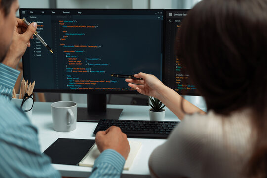 Team skilled developers program coding discussing creative website planning software project on two screen monitor's full stack data analyzing design at office with back side view concept. Postulate.