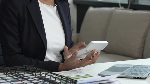 A young African American woman in a blue formal shirt with afro brown hair works as a product designer in a modern office, utilizing skills in design, CAD, CNC, and CNF.