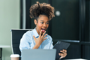 Exuberant and triumphant, a young African American woman in a blue formal shirt with afro brown...