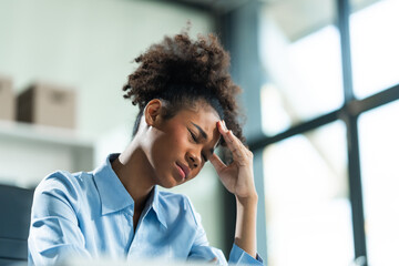 A young African American woman with Afro brown hair in a modern office experiencing panic,...