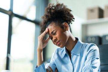 A young African American woman with Afro brown hair in a modern office experiencing panic, business-related stress, frustration, and anxiety.