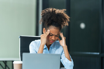 A young African American woman with Afro brown hair in a modern office experiencing panic,...