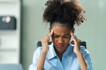 A young African American woman with Afro brown hair in a modern office experiencing panic,...