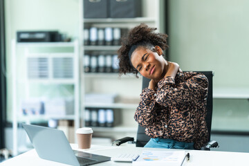 A young African American woman with Afro brown hair in a modern office experiencing office syndrome, including pain, stress, tiredness, and various physical and mental health issues.