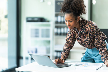 A young African American woman in a blue formal shirt with afro brown hair works as a product...