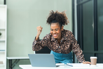 A young African American woman in a blue formal shirt with afro brown hair works as a product designer in a modern office, utilizing skills in design, CAD, CNC, and CNF.