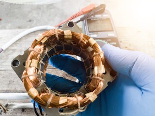 fan winding repair by a technician using blue gloves, fan motor winding repair concept.