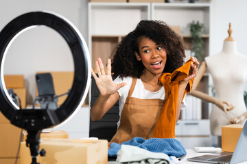 A young African American woman with afro brown hair works in a modern office, managing her online...
