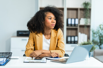 A young African American woman with Afro brown hair in a modern office experiencing panic,...