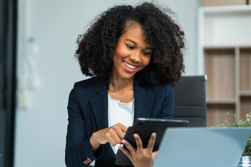 A young African American woman in a blue formal shirt with afro brown hair works as a product...