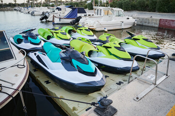 Colorful rental jet skis parked in two rows on a floating dock in a marina. Concept of water sports...