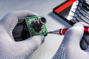 technician repairs CCTV camera in repair shop.