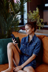 Obraz premium Young woman sitting on a couch, absorbed in her cell phone, engrossed in digital world