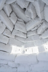 An inside view of a wall of snow bricks and a window made of ice in an igloo, a traditional shelter from the cold of the northern peoples