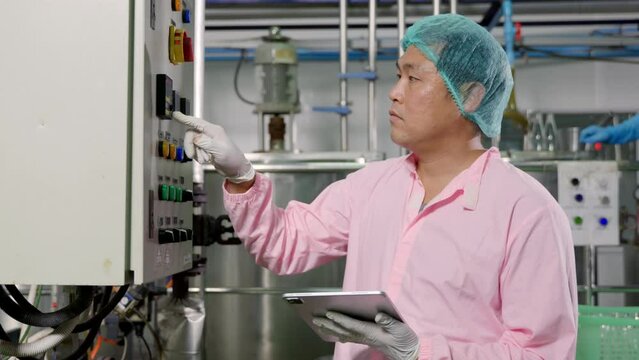 Worker employs tablet in beverage production while an engineer supervises soda water filling. Emphasizing quality control ensures top industry standards for bottle manufacturing.