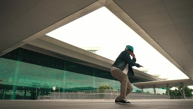 Happy hipster practice b boy dance with stylish cloth at building. Skilled street dancer enjoy show footstep performance. Modern lifestyle, break dancing. Slow motion. Outdoor sport 2024. Sprightly.