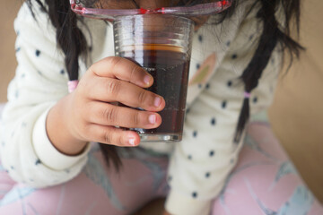 child drinking glass of soft drinks