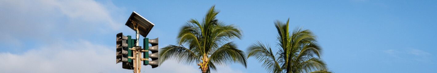 Topical setting with solar powered tsunami sirens and palm trees, pacific ocean tidal wave warning...