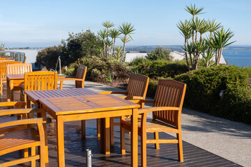 Outdoor table and chairs for tourists to relax outside in a landscaped garden with an ocean view in...