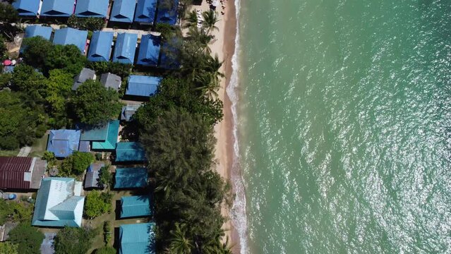 aerial view of a paradisiacal beach with palm trees and boats sailing in the crystal clear waters.