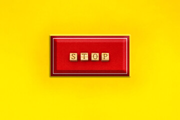 黄色い背景の四角いSTOPの英語ブロックの赤いボタン