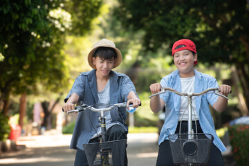 Asian preteen boys riding bikes around their community park in the afternoon during their summer...