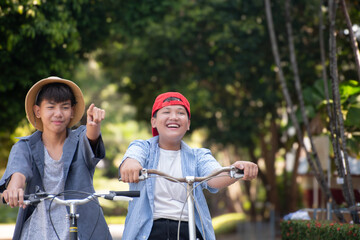 Asian preteen boys riding bikes around their community park in the afternoon during their summer holiday together, recreational activity of children concept.