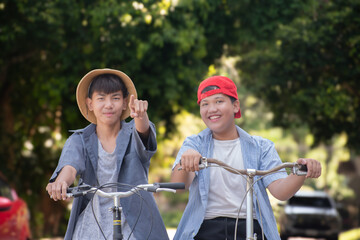 Asian preteen boys riding bikes around their community park in the afternoon during their summer holiday together, recreational activity of children concept.