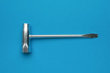 A metal key for a spark plug on a blue background.
