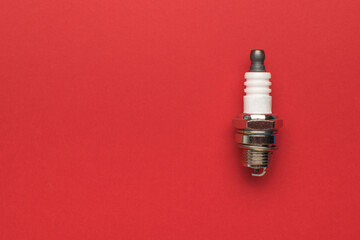 A small spark plug on a bright red background.