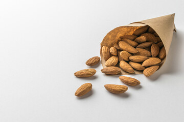 A paper bag with scattered almonds on a light background.