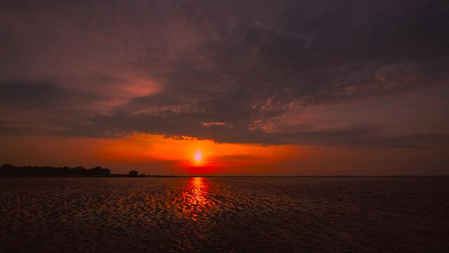 Time lapse of the Wadden Sea sunset at Hooksiel, North Germany with clouds sky moving and reflection