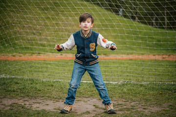 The boy is standing in the gate. A young football player is waiting for the ball.