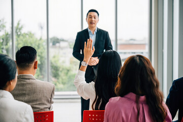 A diverse audience in a conference raises their hands for questions, voting, or volunteering, emphasizing teamwork and audience interaction during this corporate event.