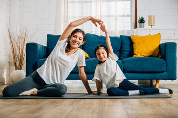 In their home an Asian mother becomes a yoga teacher for her daughter promoting strength harmony...