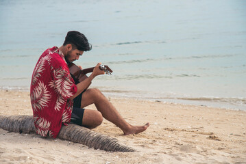 Young men playing acoustic guitar on the beach. Happy man person playing acoustic guitar music...